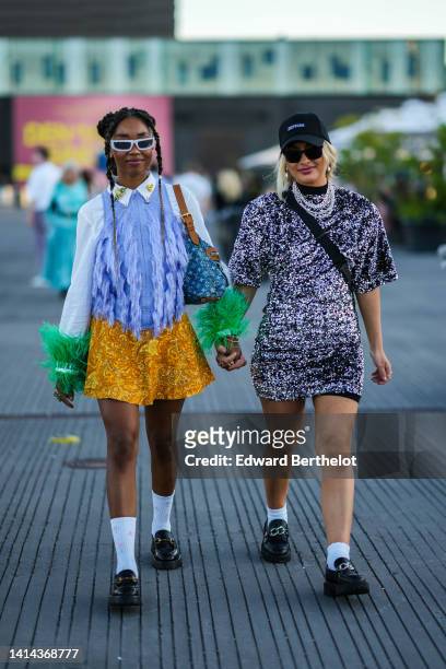 Guest wears pale blue sunglasses, silver hair rings, a white shirt with gold embroidered details on the neck / pale purple fringe chest / large green...
