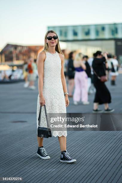 Guest wears black sunglasses, a white latte cut-out pattern halter-neck / sleeveless / midi dress, a rhinestones necklace, a silver watch, a black...