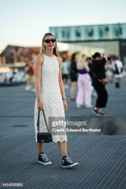 Guest wears black sunglasses, a white latte cut-out pattern halter-neck / sleeveless / midi dress, a rhinestones necklace, a silver watch, a black...