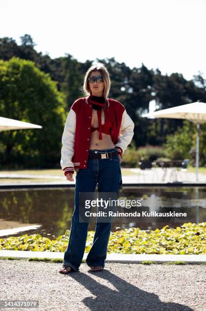 Emma Noi wearing red crop top, blue jeans and red and white sweater posing outside Skall Studio during Copenhagen fashion week Spring / Summer 2023on...