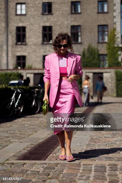 Renia Jaz wearing silk pink midi skirt, pink and purple crop top, pink blazer and green bag posing outside OperaSport during Copenhagen fashion week...
