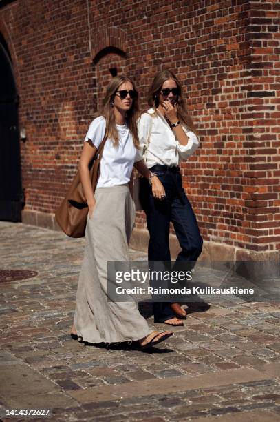 Guest wearing long grey skirt, white T-shirt and big brown bag and a guest wearing dark blue denim pants and white shirt and brown open slippers...