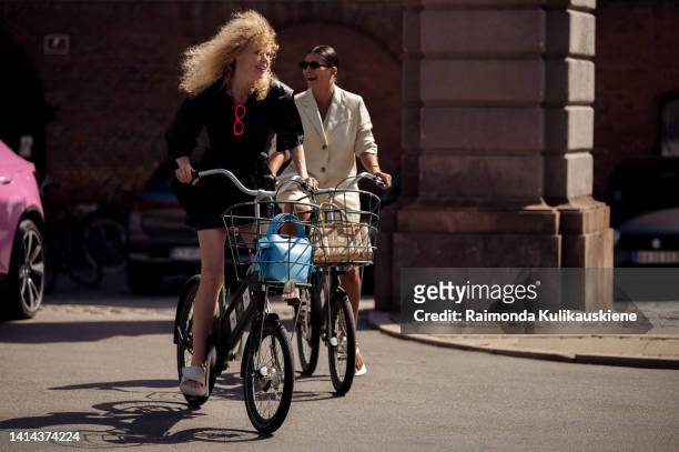 Guests driving bicycles posing outside OperaSpo during Copenhagen fashion week Spring / Summer 2023 on August 10, 2022 in Copenhagen, Denmark.