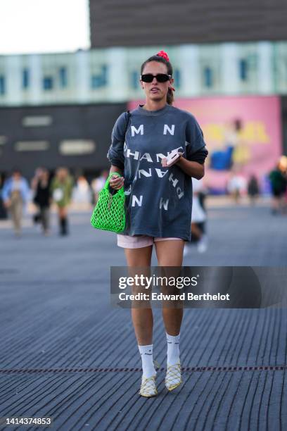 Guest wears a red and white print pattern hair clips, black sunglasses from Prada, gold earrings, a gray with painted white inscription pattern...