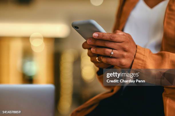 woman sending a text message, browsing social media or surfing the internet on her phone while sitting in the living room at home. closeup of the hands of a black female holding wireless technology - smart card stock pictures, royalty-free photos & images