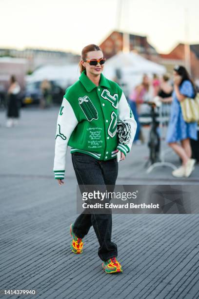 Guest wears sunglasses, a green felt with white long sleeves leather and embroidered patch teddy coat from Louis Vuitton, black denim large pants,...