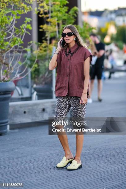 Guest wears black sunglasses, earrings, a burgundy sleeveless / shirt with black pearls pendant collar, beige with black leopard print pattern...