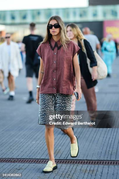 Guest wears black sunglasses, earrings, a burgundy sleeveless / shirt with black pearls pendant collar, beige with black leopard print pattern...