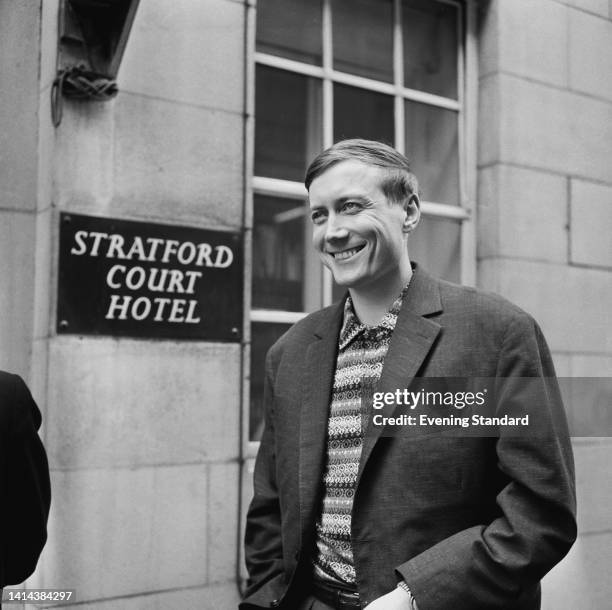 Soviet-born Russian author, poet and academic Yevgeny Yevtushenko wearing a suit jacket over a patterned shirt, smiling as he passes the Stratford...