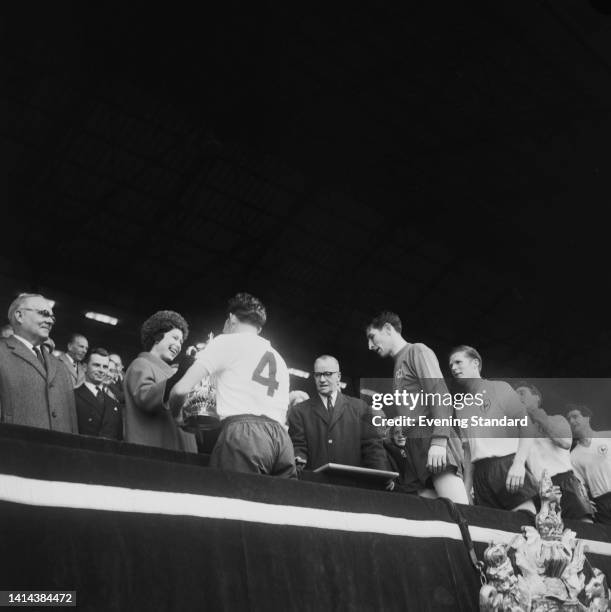 British Royal Queen Elizabeth II presents Northern Irish footballer Danny Blanchflower , the Spurs captain, with the trophy as British goalkeeper...