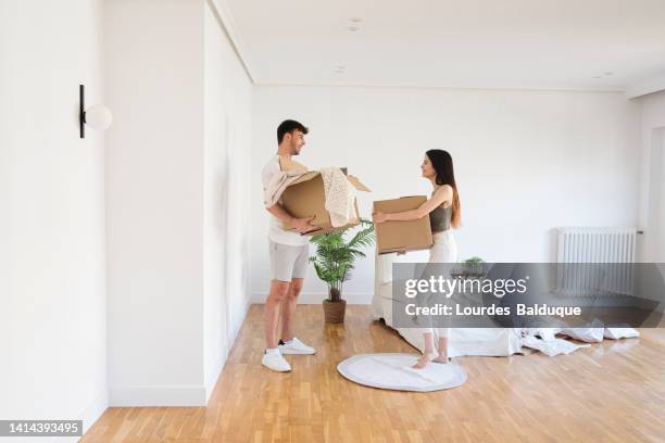 couple moves cardboard boxes in box at home - new house imagens e fotografias de stock