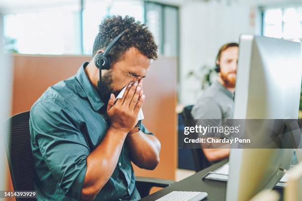 doente, covído e agente de call center doente soprando seu nariz e espalhando germes em um espaço de escritório. um agente de atendimento e suporte ao cliente africano que sofre de um sintoma de gripe ou resfriado no trabalho - espirrando - fotografias e filmes do acervo