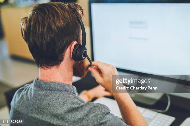 rückblick-call-center-agent, der auf einem headset spricht, während er auf einem computerbildschirm in einem büro arbeitet oder hilft. männlicher berater, der einen helpdesk für kundenservice und vertriebsunterstützung betreibt - handhaben stock-fotos und bilder