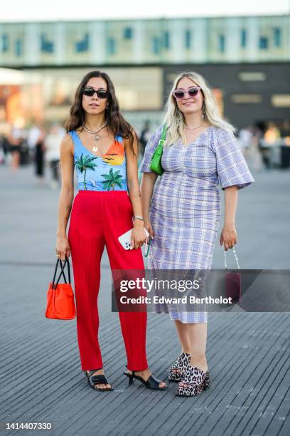 Guest wears black sunglasses, a white pearls necklace, gold shell and butterfly pendant necklaces, a multicolored landscape print pattern V-neck /...