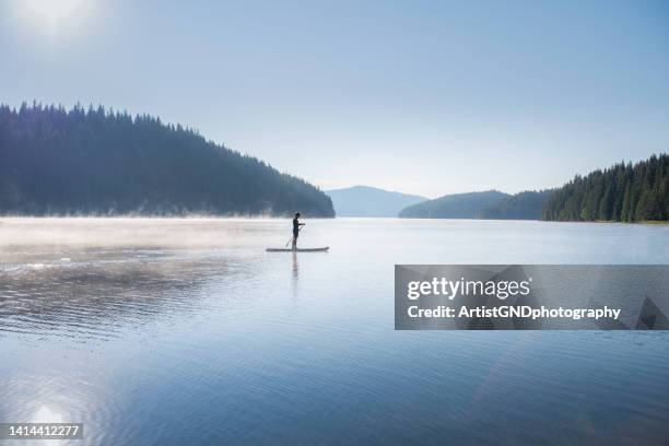 man on a paddle board in the morning. - paddle board men imagens e fotografias de stock