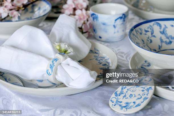 Elegant Easter table setting with empty marine ornament painted porcelain tableware, plates and bowls, Easter eggs decorations on white tablecloth....