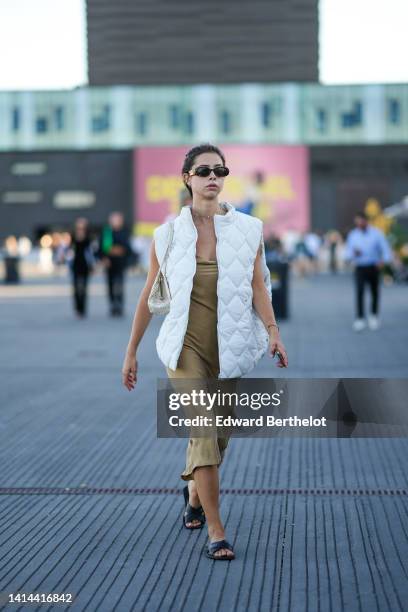 Guest wears sunglasses, earrings, a silver chain necklace, a white quilted pattern sleeveless long gilet, a beige and white snake print pattern...