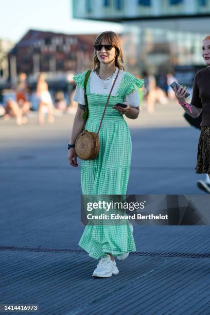 Guest wears black sunglasses, a white t-shirt, a white and green small checkered print pattern square-neck / puffy short sleeves / long ruffled...