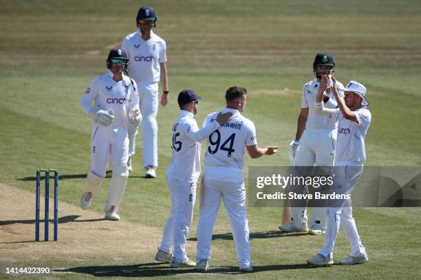 Liam Patterson-White of England Lions celebrates taking the wicket of Kyle Verreynne of South Africa caught and bowled with his team mates during day...