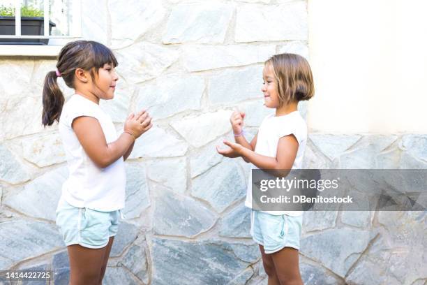 girls sisters and friends playing rock paper scissors, singing, before putting their hands out. concept of summer, playing, sisters, friends, twins and having fun. - rock scissors paper stock-fotos und bilder