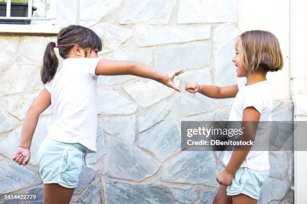 girls, sisters and friends playing rock-paper-scissors, one of them taking out the rock and the other wrapping it with the paper. concept of summer, playing, sisters, friends, twins and having fun. - scissors paper stone stock pictures, royalty-free photos & images