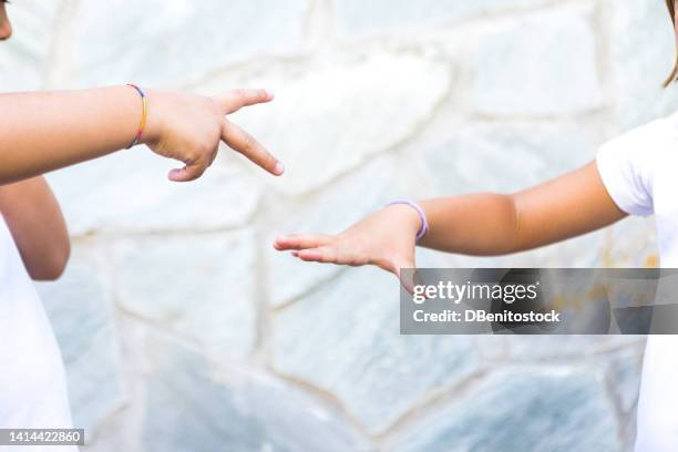 detail of the arms and hands of girls, sisters and friends playing rock-paper-scissors, one of them taking out rock and the other paper. concept of summer, playing, sisters, friends, twins and fun. - scissors paper stone stock pictures, royalty-free photos & images