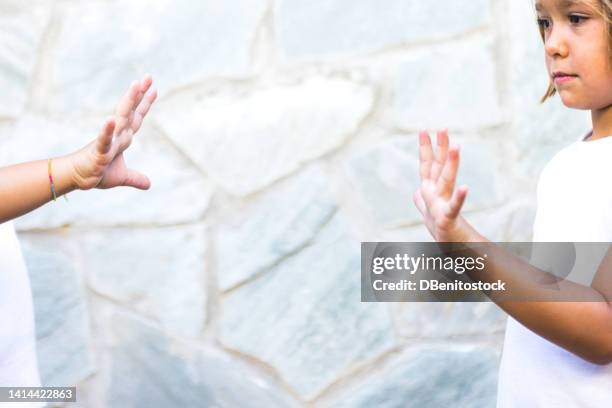 detail of the arms and hands of girls, sisters and friends playing rock-paper-scissors, both taking out paper. concept of summer, playing, sisters, friends, twins and having fun. - scissors paper stone stock pictures, royalty-free photos & images