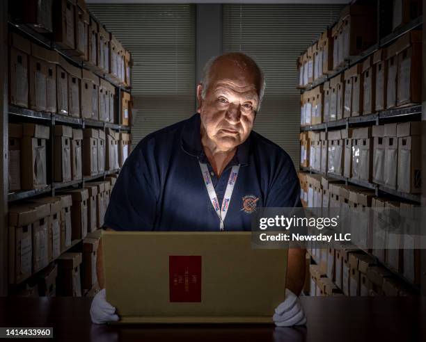 Islip, New York, town historian George Munkenbeck holds a bound volume as he works amongst stacks of historical files at his office in Islip, New...