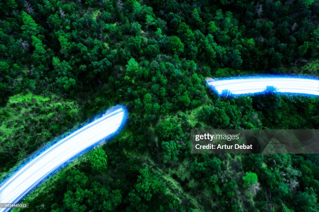 Blue light trails flowing fast in a highway with tunnel and nature, with sustainable and zero emissions transport.