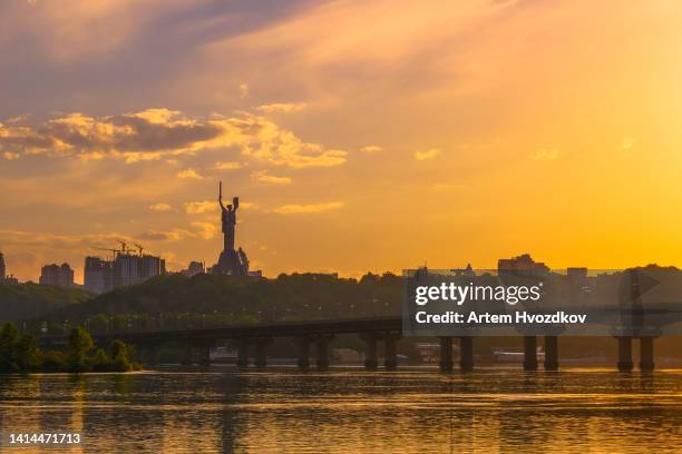 monument of mother motherland. summer cityscape view. vibrant yellow colored sky - kiew stock-fotos und bilder