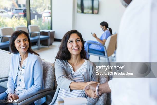 mother watches as her daughter shakes hands - greeting friends stock pictures, royalty-free photos & images