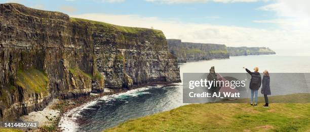 two woman friends looking at coastline cliffs - irish family stock pictures, royalty-free photos & images