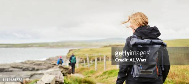 woman walking along a narrow pathway on cliff - beautiful irish person stockfoto's en -beelden