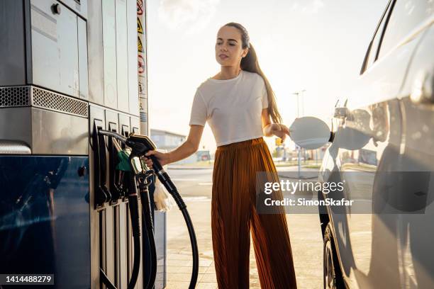 young woman refueling her car at gas station - filling petrol stock pictures, royalty-free photos & images