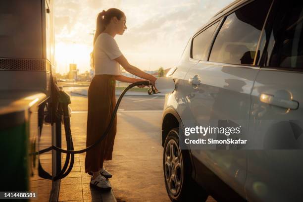 young woman refueling her car at gas station - diesel fuel stock pictures, royalty-free photos & images