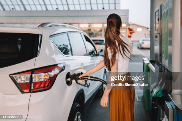 young woman refueling her car at gas station - abastecer imagens e fotografias de stock