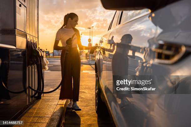 young woman refueling her car at gas station - bensinstation bildbanksfoton och bilder