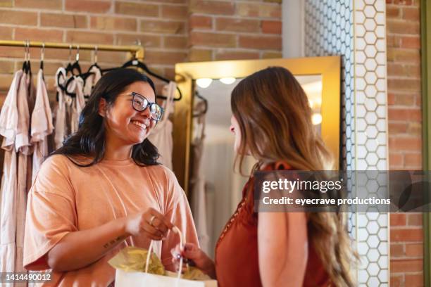 hispanic and white females in small town america boutique using credit cards and electronic devices payments on the go photo series - gift shop interior stock pictures, royalty-free photos & images