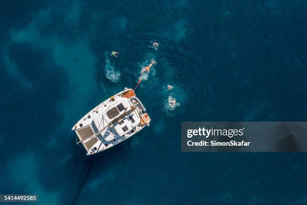 high angle view of distant people swimming by modern sailboat on sea - croatia people stock pictures, royalty-free photos & images