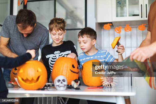 family celebrating halloween at home and preparing pumpkins - pumpkin decorating stock pictures, royalty-free photos & images