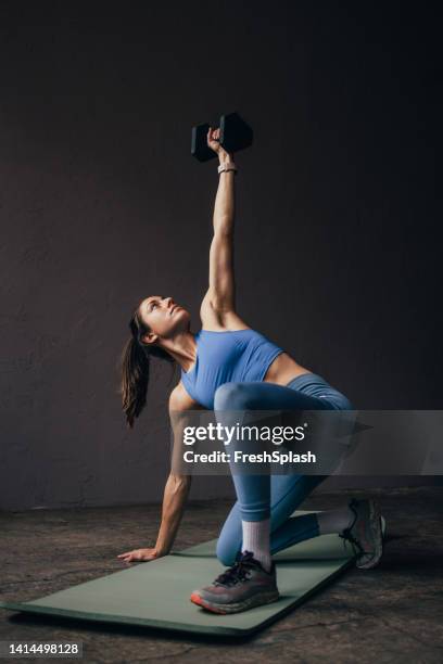 mujer haciendo un entrenamiento con una mancuerna - mancuerna fotografías e imágenes de stock