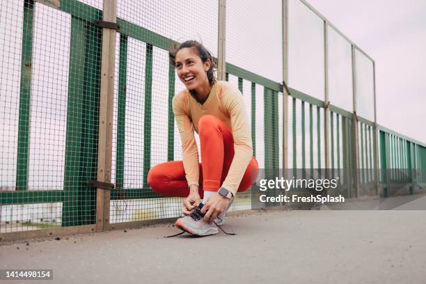 female athlete tying her shoelaces - amarrado imagens e fotografias de stock