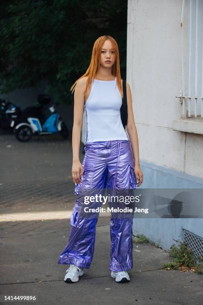 Model Jan Baiboon wears a side-clasp white tank top, metallic purple raver cargo pants, and white New Balance sneakers after the Rains show at Le...