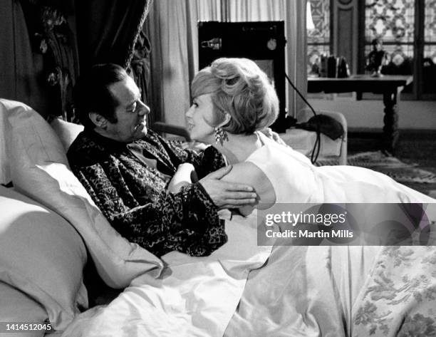 English actor Rex Harrison , embraces American comedienne, actress, singer and businesswoman Edie Adams , during a scene for the film 'The Honey Pot'...