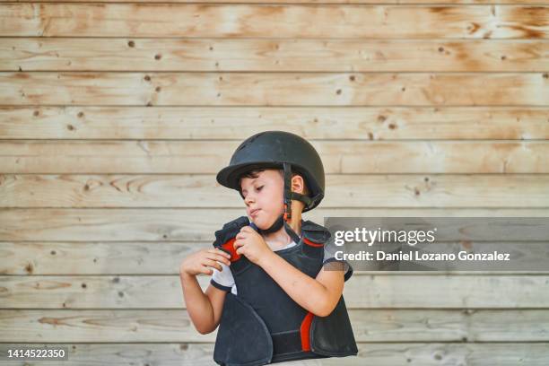 boy taking off jockey vest - protective sportswear stock pictures, royalty-free photos & images
