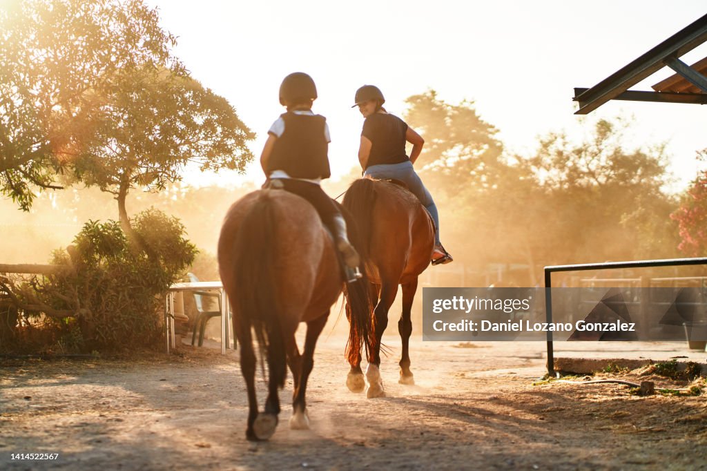 Mother and son riding horses at sunset