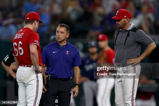 Team trainer Matt Lucero and Manager Chris Woodward of the Texas Rangers check on Josh Sborz of the Texas Rangers after Sborz was hit by a line drive...