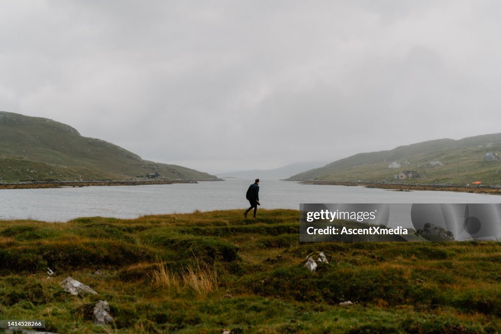 Hiker looks out at moody sky and bay