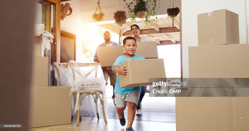 Glückliche Familie, die in ein neues Zuhause zieht und fröhlicher oder aufgeregter Kindersohn und Eltern, die Kisten in ihr Haus tragen. Erstmalige Hausbesitzer, die mit Immobilien zufrieden sind, während sie sich niederlassen