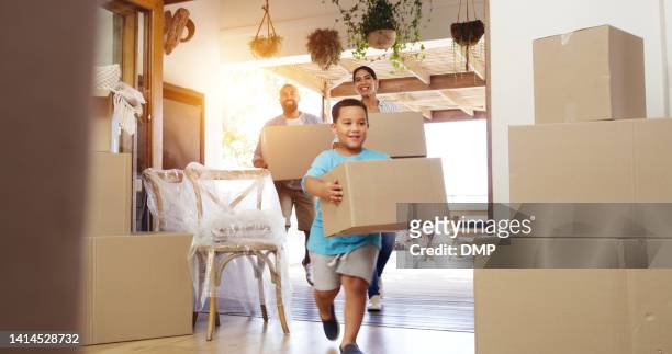 happy family moving into new home and cheerful or excited child son and parents carrying boxes into their house. first time home owners looking satisfied with real estate property while settling in - verhuizen stockfoto's en -beelden